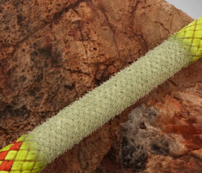 Close-up of a textured, green and yellow Mammut climbing rope against a rugged, rocky background.