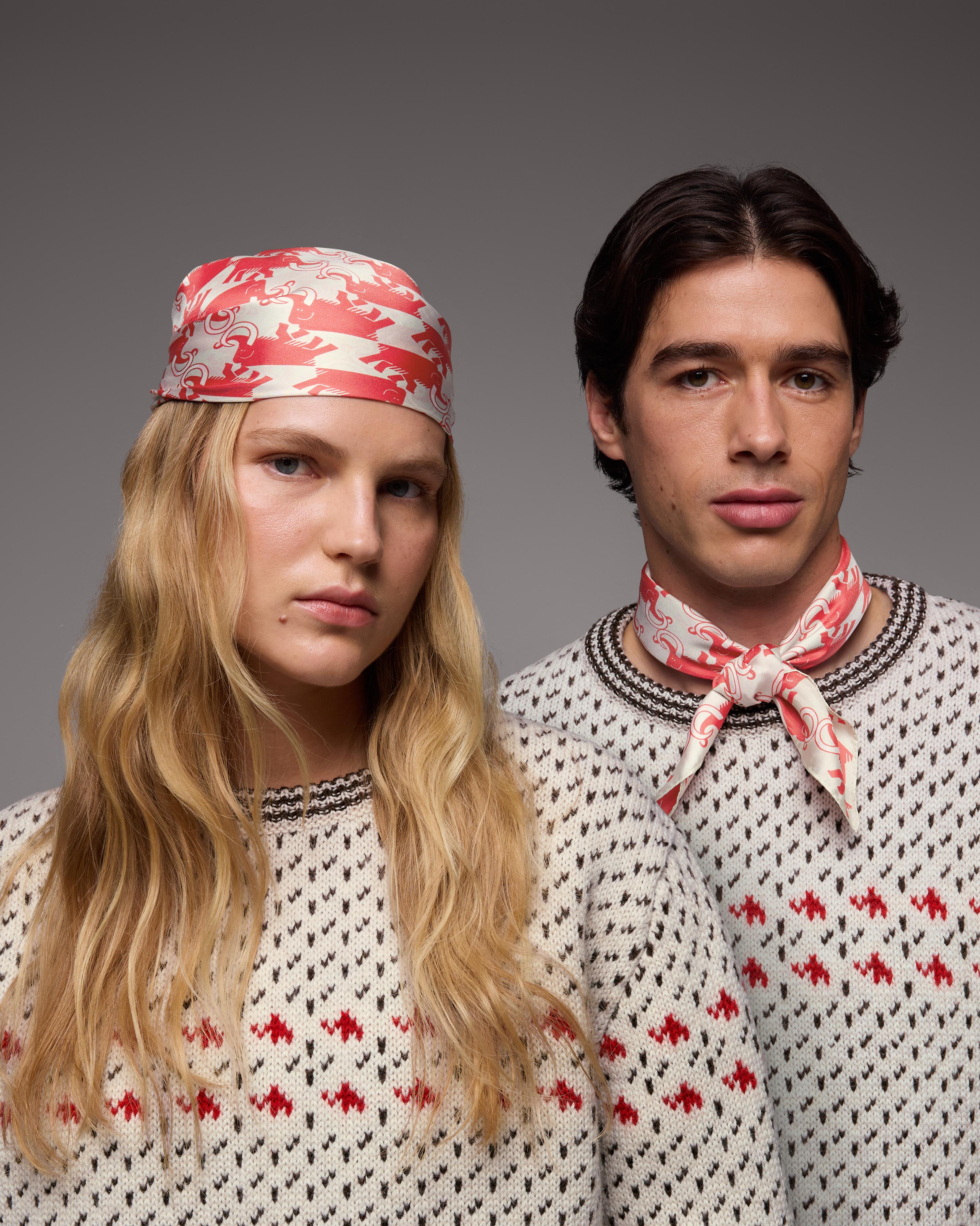 Two people in matching Mammut sweaters with red designs; one wears a headscarf, the other a neck scarf, both showing branded style.